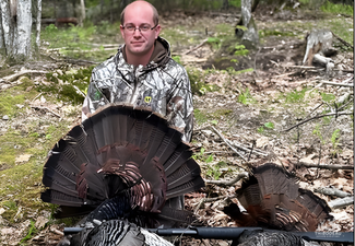 Hunter displaying two harvested wild turkeys during spring season