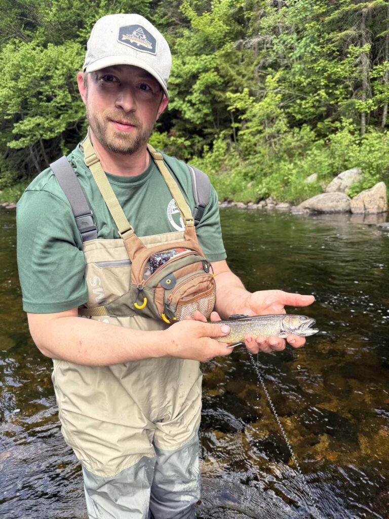 A Registered Maine Guide holding a landlocked salmon on a Maine river
