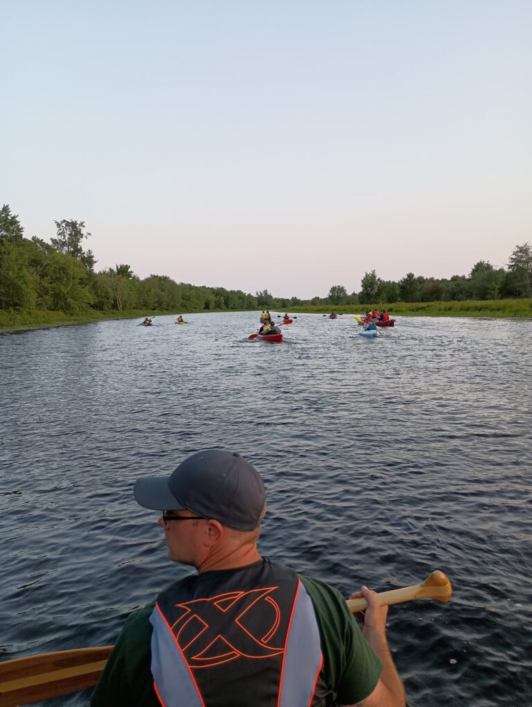 A group paddling canoes down a Maine river on a guided trip