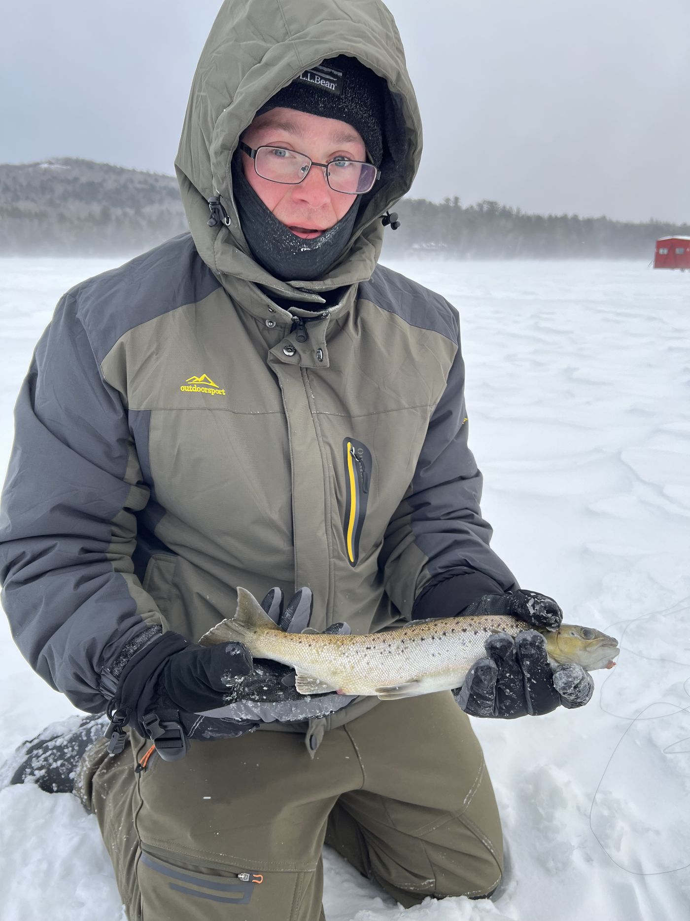 Angler on a frozen Maine lake holding a brown trout