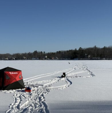 An ice fishing shelter set up on a frozen Maine lake