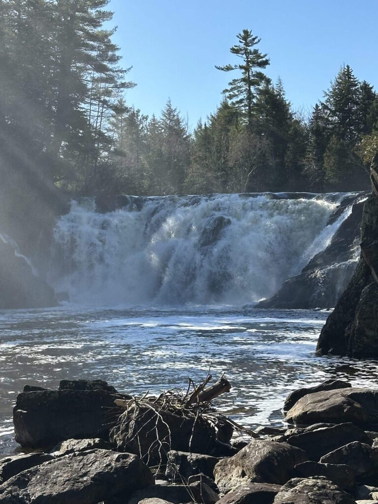 Sunlight falling across a Maine waterfall on a guided waterfall hike