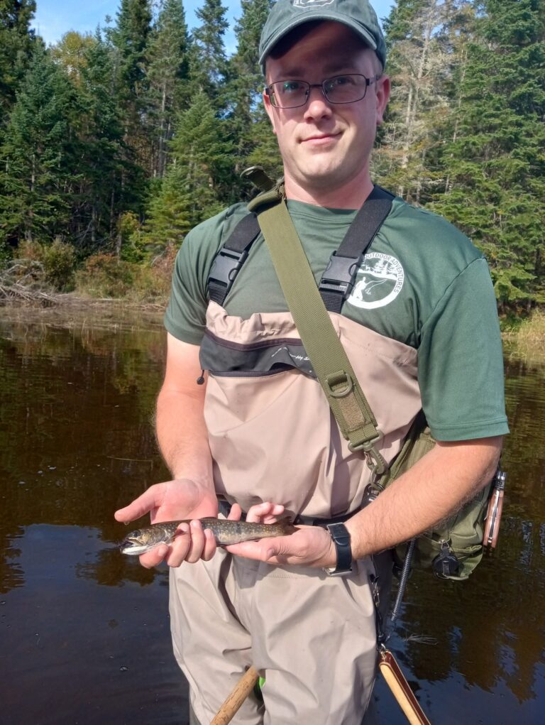 A Registered Maine Guide holding a brook trout on a Maine river
